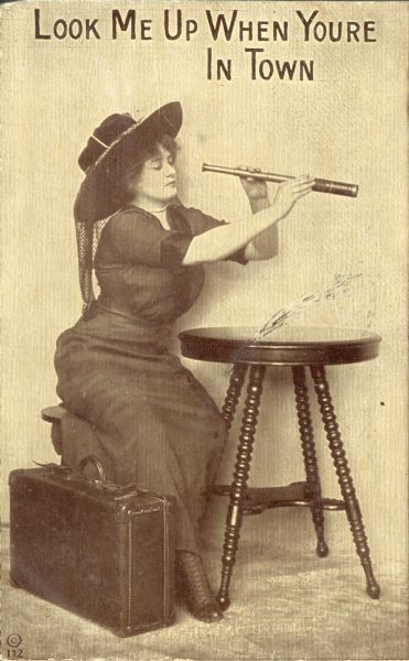 Postcard of woman seated at table and looking through a telescope. Text reads "Look Me Up When Your [sic] In Town."