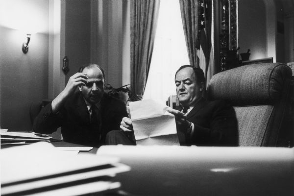 Senator Gaylord Nelson and Senator Hubert Humphrey seated at a desk reviewing papers.