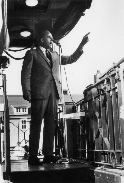 Side view of Gaylord Nelson speaking from a train caboose while on the campaign trail during a whistle stop tour.