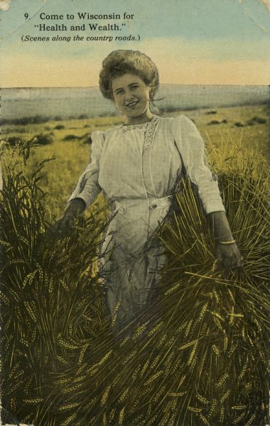 Smiling woman in white dress posing in a wheat field.