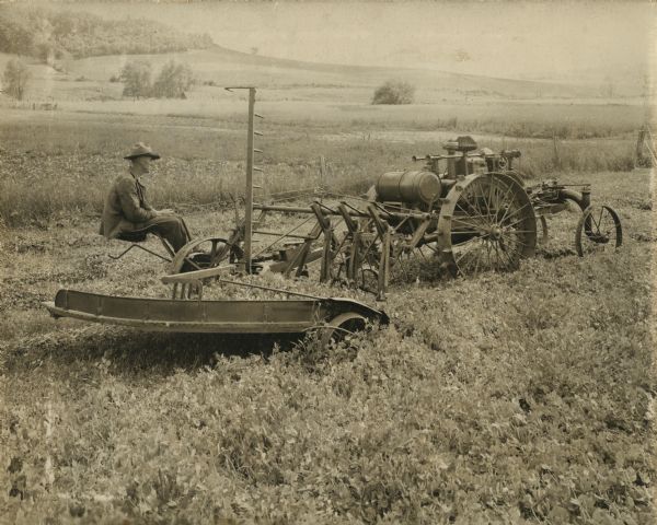 Man sitting behind a La Crosse tractor on a thresher.