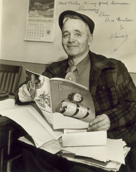 Autographed photograph of Chauncey "The Bear Hunter" Bottum reading a magazine called <i>Traveler</i>. The autograph is for Governor Goodland, and reads "Best wishes to my good Governor."