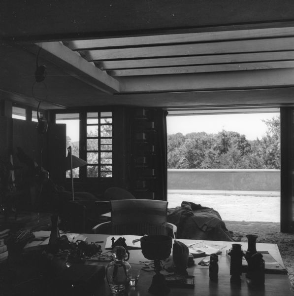 Southwest wall of Frank Lloyd Wright's bedroom at Taliesin, his home in Wisconsin. In the background is a large, open doorway leading out onto a balcony with treetops beyond. Taliesin is located in the vicinity of Spring Green, Wisconsin.