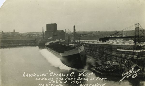 Elevated view of the ship the <i>Charles C. West</i> splashing into the Manitowoc River with a large crowd gathered to watch.