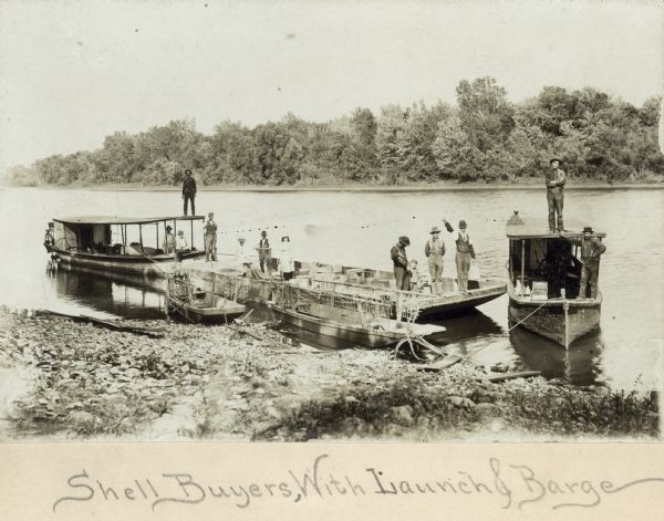 Prairie du Chien (vicinity) about 1895-1900. Shell buyers with their launches and barges docked at shoreline. Freshwater clam shells were used in the pearl button industry in this area.
