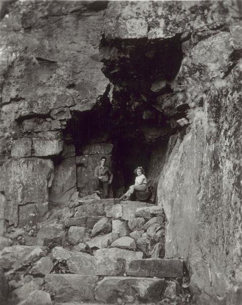 A young boy and girl posed inside of the Elephant Cave in the east bluffs at Devil's Lake State Park.