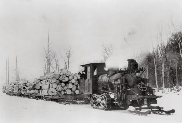Steam log hauler made by Phoenix Manufacturing Company of Eau Claire, pulling loaded skids through snow. Rice Lake lumber camp, overland spur.