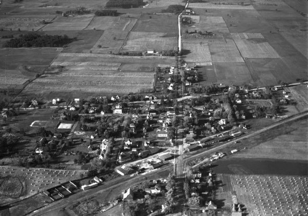 Aerial view of Verona including businesses, houses, and the surrounding farm land.