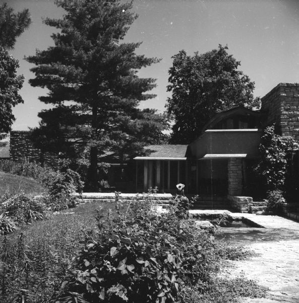 Northwest elevation of Taliesin showing the a portion of the garden room, Wrights' bedroom, and the gardens. Taliesin was the summer home of architect Frank Lloyd Wright. There is a pool surrounded by stone near the corner of the house. Taliesin is located in the vicinity of Spring Green, Wisconsin.