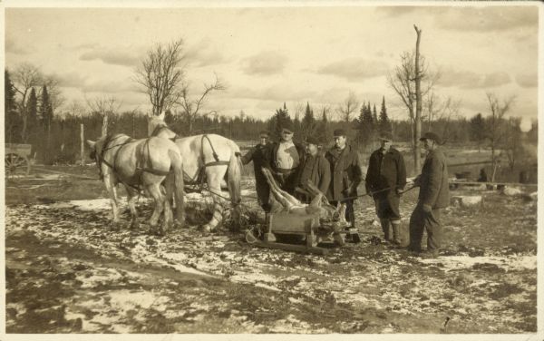 Bringing in two small bucks, dead and loaded on a sled behind a team of horses, Old Camp 2. The third man from the right is Clarence Deitz.