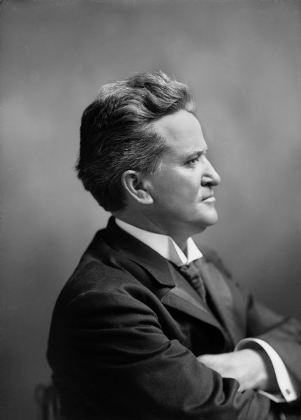 Profile portrait of Robert M. La Follette, Sr. with his arms crossed.  The photograph was taken during during his first year in the U.S. Senate, but it was taken in Madison.