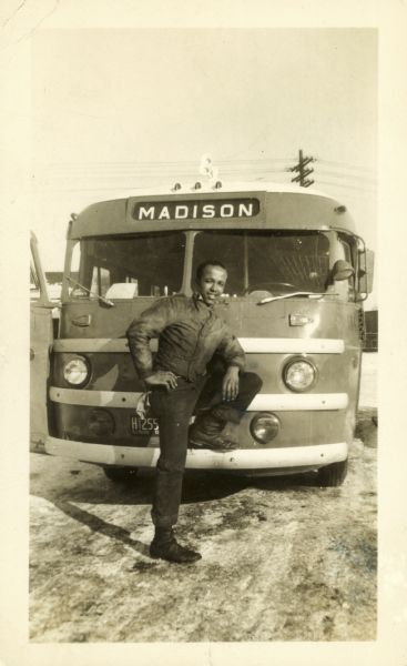 Lewis R. Arms poses in front of a Greyhound Bus that displays the destination "Madison" above the windshield. Arms worked for Greyhound at the time.