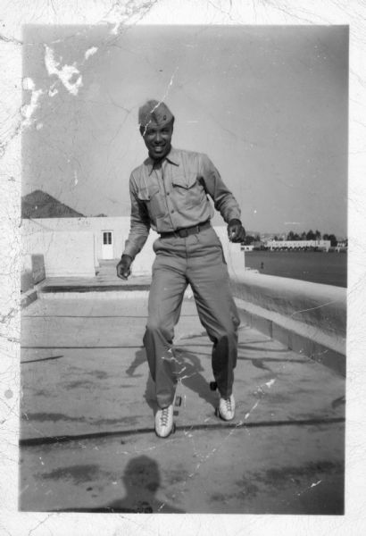 Lewis R. Arms is shown in military uniform, wearing roller skates on what appears to be a roof. There is a signature on the back of the photograph that reads, "Evelyn from Lewis."