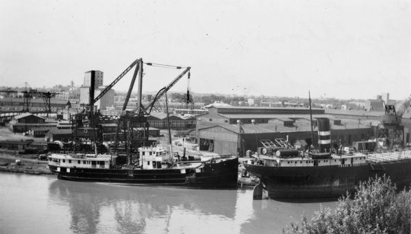 Elevated view across river of the S.S. <i>Hyacinth</i> of the U.S. Lighthouse Service being repaired at the Manitowoc Ship Building Company dock. The <i>Frank H. Goodyear</i> is docked at the right.