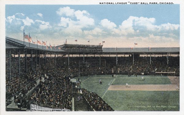View from the upper right field corner of a baseball game in progress at the National League Ball park in Chicago. The stands are filled with spectators and American flags fly from the roof of the ball park. Caption reads: "National League 'Cub'" Ball Park, Chicago."