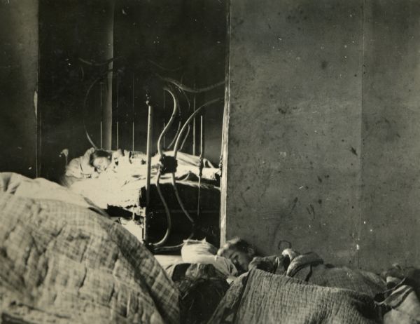 Two children lying sick in bed during the Spanish Flu epidemic.