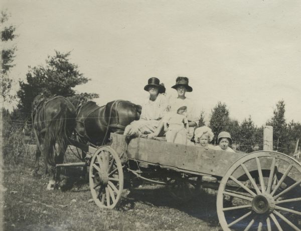 Theta Mead in a horse-drawn wagon along with another woman and three children.
