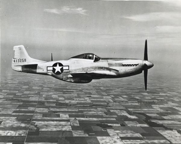 P-51 Mustang U.S. fighter plane over rural area.
