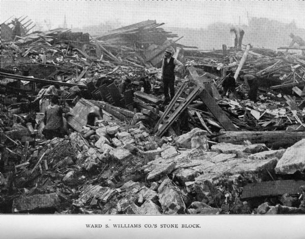 People stand among the rubble of Ward S. Williams Co.'s stone block building after a tornado.