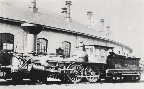 CM&StP Railway locomotive no. 71 and a coal car at a roundhouse.