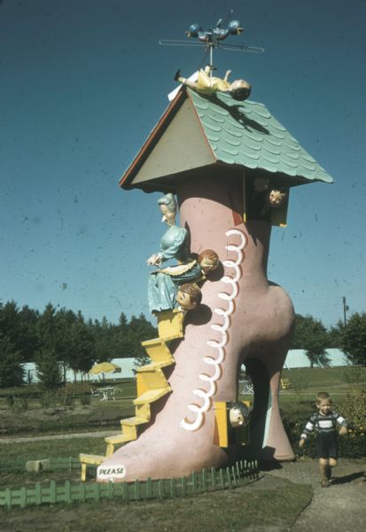 Young boy running down the path leading away from an attraction depicting a scene from the nursery rhyme "The Old Woman Who Lived in a Shoe," part of Storybook Land.