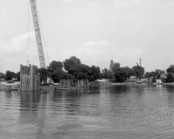 View across water of early construction of the bridge over Little Lake Buttes des Morts.