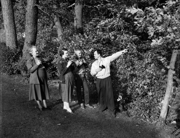 Mary Walker, vice-president of the Audubon Society; Gratia Stavrum, Alan Keitt, and Thomas J Stavrum, president of the Audubon Society, enjoying a bird walk. They are all carrying binoculars.