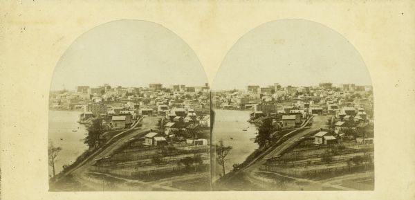 The third Wisconsin State Capitol (the second in Madison), from Governor Farwell's Octagon House, probably early in 1862. Also visible in the downtown are the Dane County Courthouse and St. Raphael Catholic Church. Frederick A. Sprecher's brewery (later Fauerbach's) is in the middle ground on the left. The foreground provides a glimpse into many backyards.