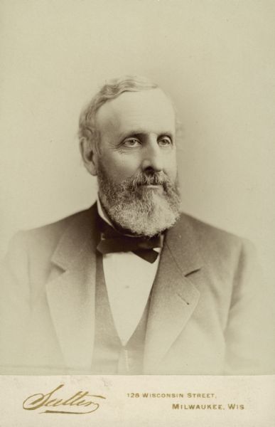 Quarter-length studio portrait of Daniel L. Wells with gray hair and a beard.