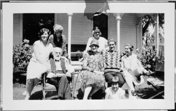 Wisconsin writer August Derleth, wearing a boldly patterned sweater and sitting with an unidentified group on a lawn in front of a house. Probably friends and family.