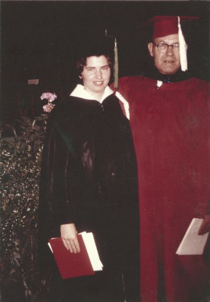 Peggy Algren (b. 1943) and her father Henry Lawrence Ahlgren at her graduation from the University of Wisconsin in 1966. At the time Henry Ahlgren was a University of Wisconsin professor and served on the Public Functions committee, which planned graduation. Part of his duties was serving as a commencement marshal, whose job was to guide the flow of students on stage. He wore his red academic gown and mortarboard while working as a marshal.