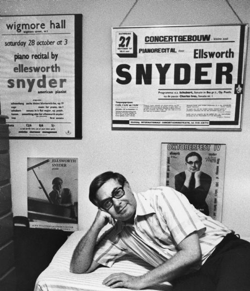 Pianist Ellsworth Snyder posing in front of posters advertising his concerts.