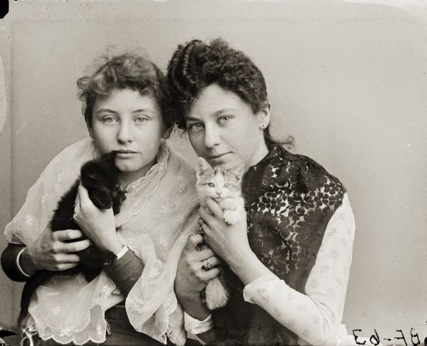 Studio portrait of Hattie (Harriet) and Nellie Bennett posing with pet kittens.