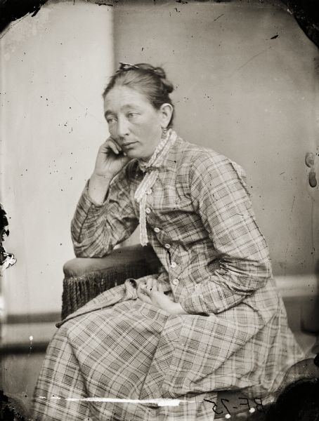 A studio portrait of Francis (Frankie) Irene Douty, the first wife of H.H. Bennett. She is sitting in a chair and is leaning her cheek on her hand.