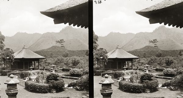 Stereograph of a view in Japan including a garden, traditional buildings and mountains in the background.