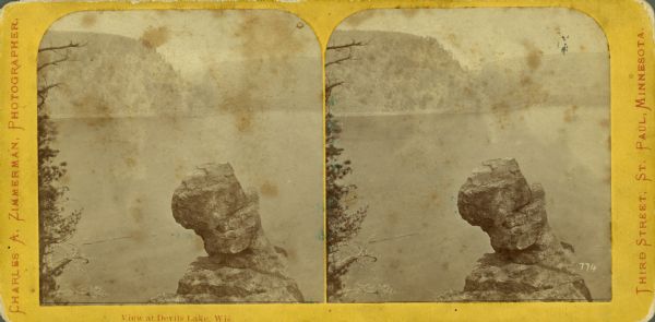 Stereograph of Devil's Lake with Turk's Head rock formation in the foreground.