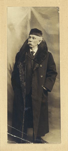 Full-length portrait of an elderly Henry Hamilton Bennett posing in a fur hat and a coat with a fur collar.