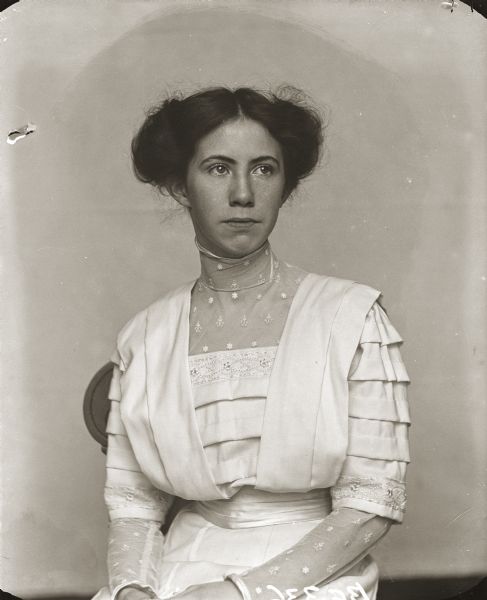 Waist-up studio portrait of Miriam Bennett sitting in a chair. She is the daughter of Henry Hamilton (H.H.) Bennett.