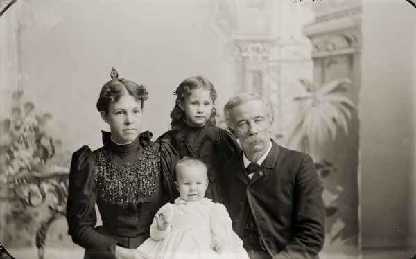 A family portrait in front of a painted backdrop of H.H. Bennett, his wife Evaline, and their daughters Miriam and Ruth.