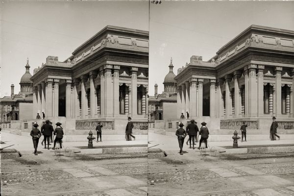 Stereograph from street of Layton Art Gallery. There are pedestrians on the sidewalk and front steps. One young boy is riding a tricycle.