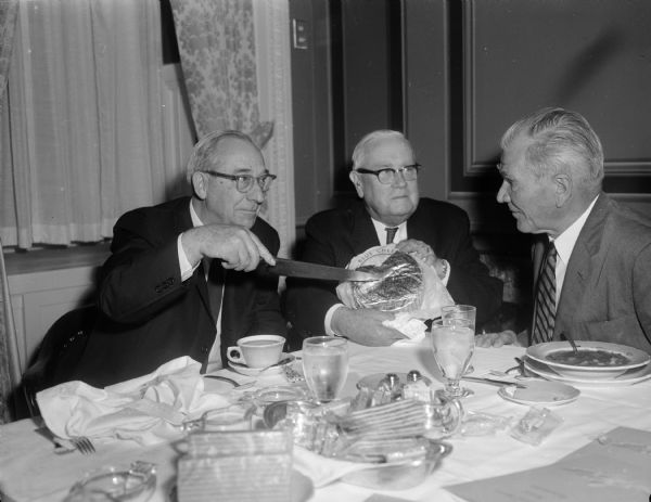 Senators Wiley (Wisconsin), Robertson (Virginia), and Jordan (North Carolina) posing with a round of blue cheese.
