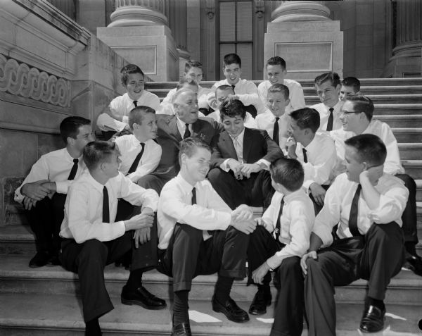 Senator Alexander Wiley posing with singer Paul Anka and senate page boys on the steps of the U.S. Capitol building.