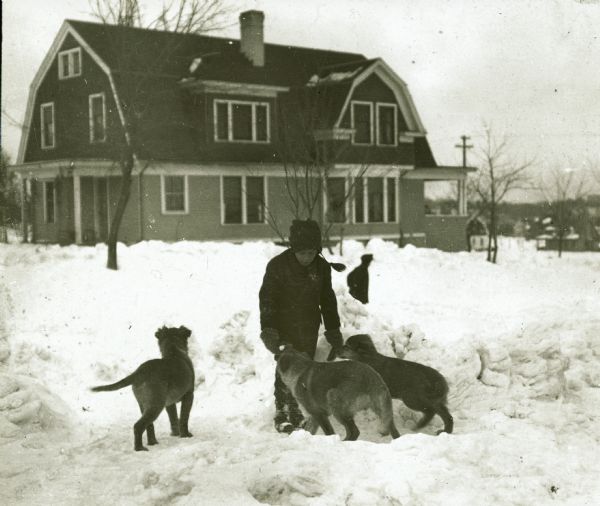 Delos Dudley outside in a snowy yard with dogs "Towser," "Fido" and "Cleo." In the background is a house.