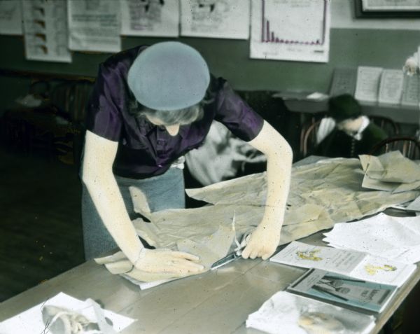 A mother is cutting a pattern from display material on a table.