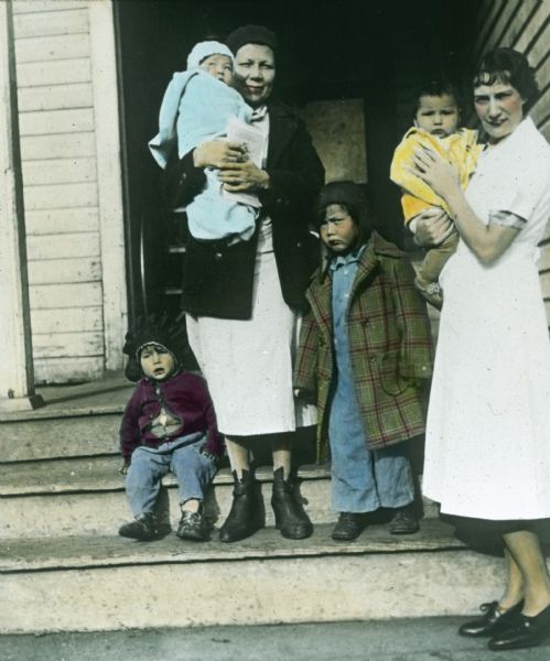A nurse poses on steps with a Native American mother and four children.
