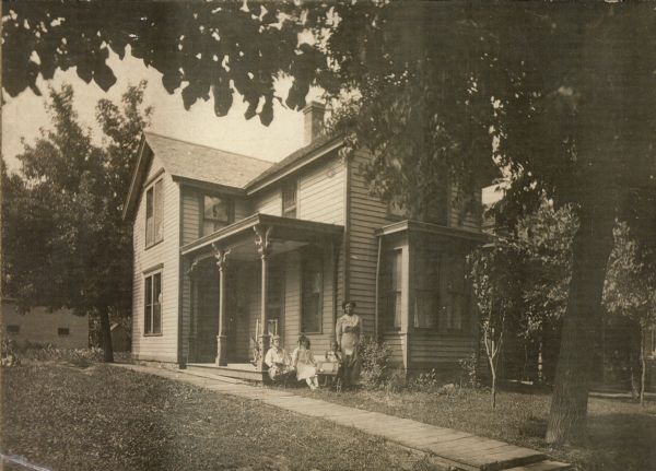 A woman and three children pose in front of the Pierce family's house on Williamson Street. From left to right are Leo Kronenberg, Gertrude Kronenberg, Theodore Pierce, and his mother Mollie Pierce.