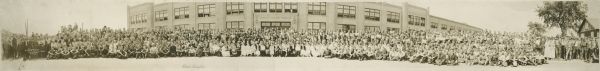 Panoramic view of Samson Tractor Factory with employees in front of building.