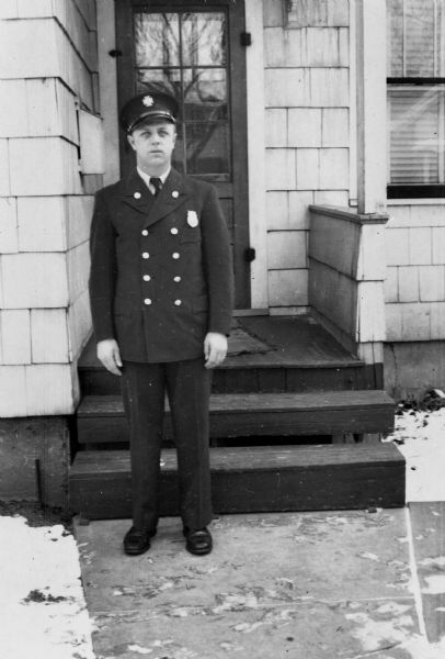 George William Piernot (1922-2000) standing outdoors wearing his Madison Fire Department uniform in front of the home of his parents George Francis and Rhody (Boyum) Piernot at 709 North Street. Piernot served as a member of the Madison Fire Department from about 1946 until his retirement in 1977. He primarily worked at stations 7 and 9, where he drove the ladder truck.