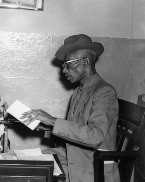 L.C. Bates seated at a desk handling paperwork.