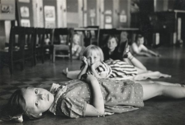 Kindergarten students laying on the floor in a row, possibly for nap time.